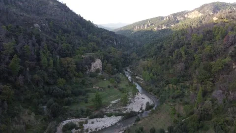 Flying Above Winding River Between Hills With Sun Creating Shadows Video stock 255705689