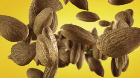 Flying of Almonds in Yellow Background Stock Footage 147483143