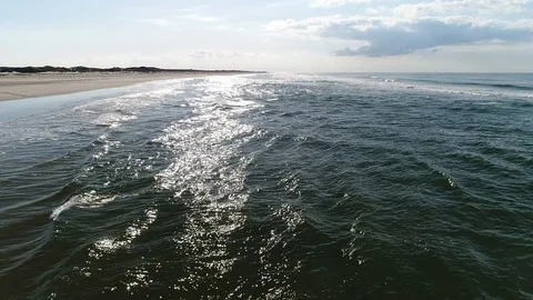 Flying along the beach fast over surf and reflection of sun Stock Footage 103354334