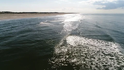 Flying along the beach over breakers reflection sun - Aerial Stock Footage 103354450