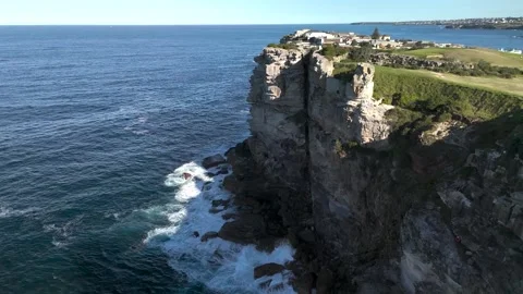 Flying along cliffs looking out to sea from aerial view on sunny day Stock-Footage 336999929