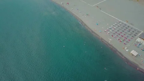 Flying along long sandy beach. Swimming and sunbathing people from above 스톡 동영상 82843061