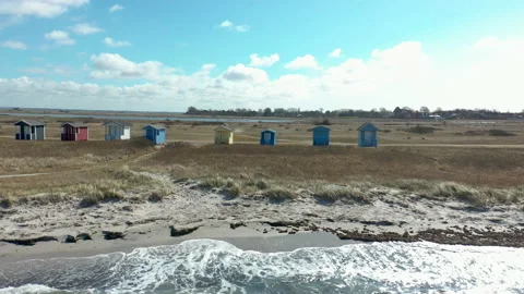 Flying along shoreline with waves rolling in over the beach and bath houses Stock Footage 152911098
