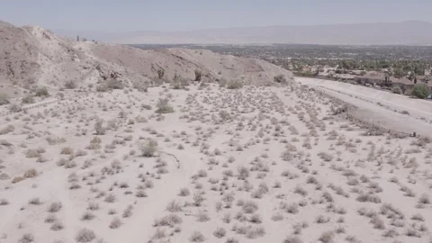 Flying along side mountain on the outskirts of desert city Stock Footage 245510294
