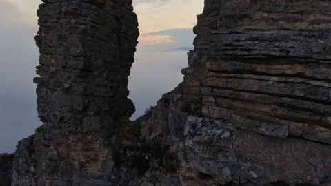 Flying among sheer cliffs against the backdrop of fog and a mountain range on th 스톡 동영상 150597277