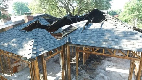 Flying up and tilting down over burned out house Stock Footage 95876301