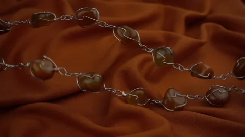 Flying and wavy motion of gems jewel on a gorgeous rust colored soft fabric in s Stock Footage 120129271