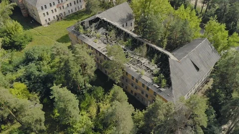 Flying around an abandoned house with a collapsed roof, trees sprout through the Видео 125731295