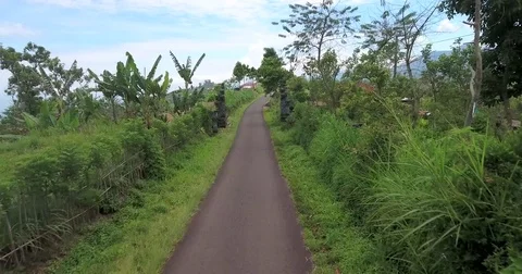 Flying around back roads of Bali on mountain top, scotter passes by Stock Footage 73099896