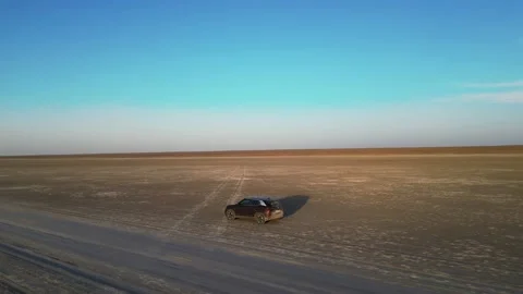 Flying around a car driving on a dried-up lake - aerial Stock Footage 238894893