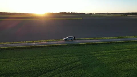 Flying around the car in the field on sunset Stock Footage 276504282