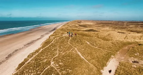 Flying around a dune with guys on it at the beach sea in the background aerial Video stock 153515600