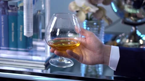 Flying around a man in a blue jacket holding a glass of whiskey in his hand 库存影片 260260955