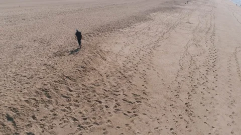 Flying Around Man Walking on Ocean Beach Stock Footage 85488190