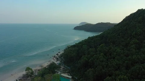 Flying around mountain covered with forest trees on a beach shore in sunset and Video stock 124326361