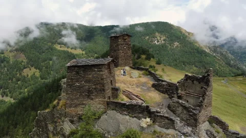 Flying around old monastery ruins with people inside surrounded by mountains Stock Footage 229879076