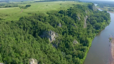 Flying around a river slope with cliffs and overgrown trees on a sunny day. Stock Footage 119075715
