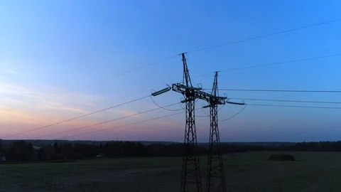 Flying around the support of a power line under the electric wires at sunset.  Stockbeeldmateriaal 94495249
