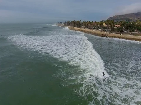 Flying around surfer, panning toward Ventura's Surfers Point, California Stock Footage 73099220