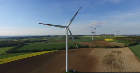 Flying around wind turbines in rape field. Video stock 62897376