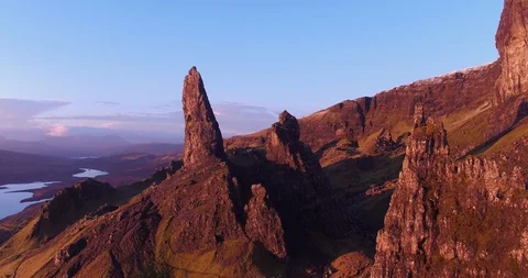 Flying away from Old Man Storr shadow cast onto mountain sunrise drone aerial 4K Stock Footage 104580159