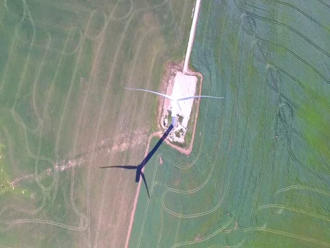 Flying Away From Rotating Wind Turbine on Green Field Aerial Shot Stock Footage 79100669