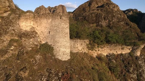Flying away from sharp rocks with little abandoned fortress in sunny evening Stock Footage 99949890