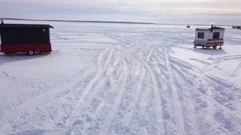 Flying back mid-air over the frozen lake and between ice fishings trailers Stock-Footage 152422487