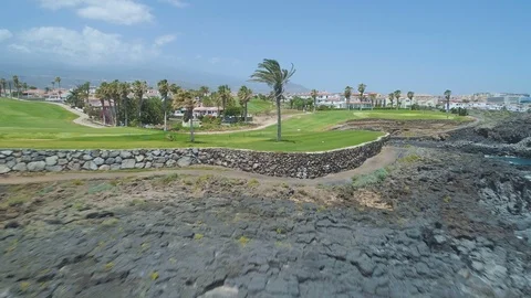 Flying back over golf course green field towards blue ocean in sunny day Video stock 89632137