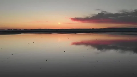 Flying backward above a reflecting sunset over a salt lake revealing a couple Stock Footage 170763445