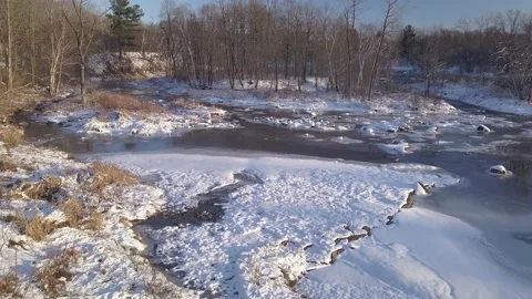 Flying backward mid-air with a drone over the frozen river with some rapids Video stock 152086149