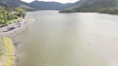 Flying backwards over a dam with people and cars unloading boats Vidéo 148609717