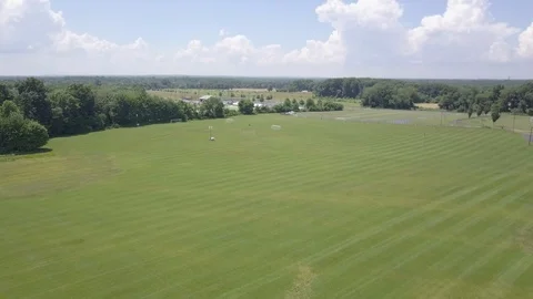 Flying backwards over flat green field street reveal Stock Footage 91866487