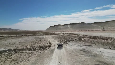 Flying behind a car driving on a mountain road in a mountain desert Stock Footage 237695129