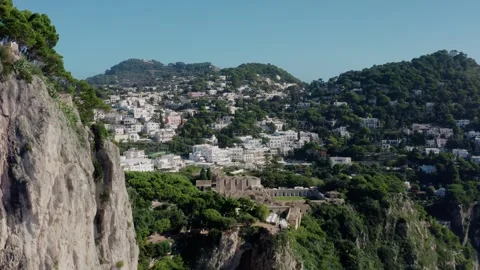 Flying Behind a Steep Limestone Cliff and Revealing a Beautiful Town in Capri Vídeo Stock 330855180