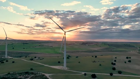 Flying behind a working wind turbine with the sun in front in cloudy sky Stock Footage 274528120