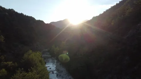 Flying between mountains next to a river and with a sunset Stockbeeldmateriaal 234129290
