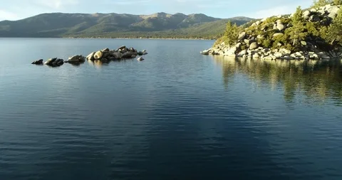 Flying between rocks on a calm reflective lake Stock Footage 98311305