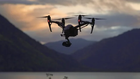 Flying black drone against mountains in sunset Stock Footage 102529606