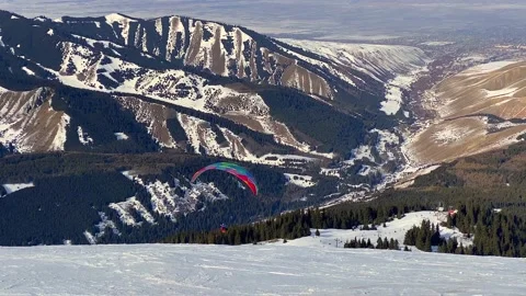 Flying on a bright colored paraglider over the Karakaol mountain ski base 動画素材 232653330