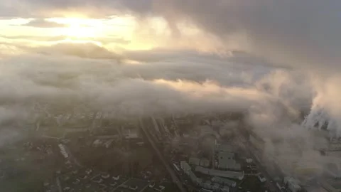 Flying into a bright sun overlooking misty morning cloudy sky in small town Stock Footage 147923333