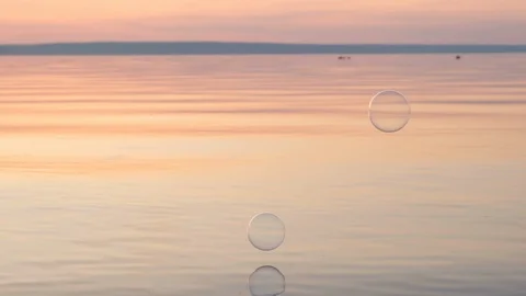 Flying bubbles over the water at sunset. Anti-stress video. Abstract video. Stock Footage 115015422
