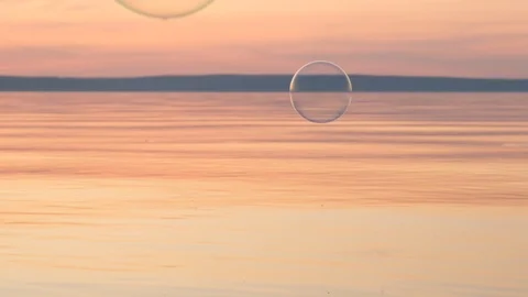 Flying bubbles over the water at sunset. Anti-stress video. Abstract video. Stock Footage 115016384