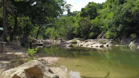 A flying camera flies low over the river overlooking the jungle and large stones Stock Footage 119120719