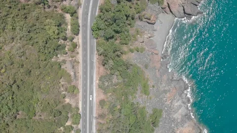 A flying camera flies over a beautiful rocky sea overlooking the winding road Stock Footage 117445022