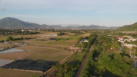 A flying camera flies over a railroad in Vietnam overlooking rice fields Video stock 100188697