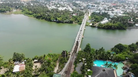 A flying camera flies over a railway bridge stretched across a river  Vietnam Stock Footage 100187850