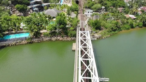 A flying camera flies over a railway bridge  a river along which Vietnam Stock Footage 100187915