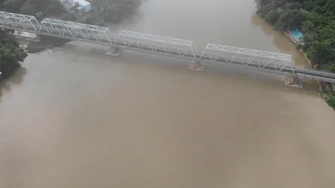 A flying camera flies over a railway bridge across a river along which Vietnam Stock-Footage 115270119