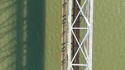 A flying camera flies over a railway bridge stretched across a river along Stock Footage 116113761